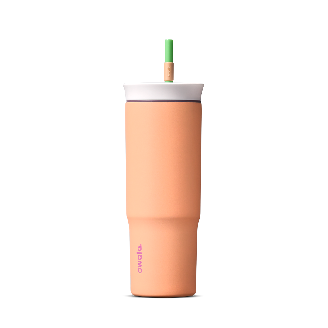 24oz Tumbler in Peachy Keen; matte peach-orange insulated tumbler with white lid and green straw, Owala wordmark on front